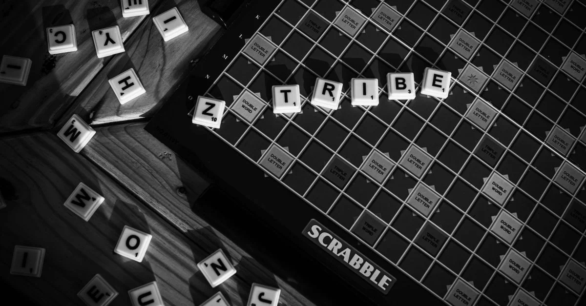 Image monochrome d'un plateau de Scrabble dont les lettres forment le mot « TRIBU ».