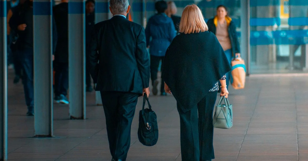 Un homme et une femme marchant avec des valises dans une gare animée.